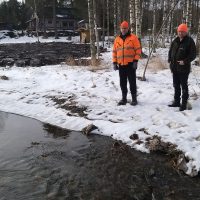Martti Lautala ja Thomas Penttilä tarkastelevat, miten vesi lorisee Aitoon kosteikon pohjakynnysen yli.